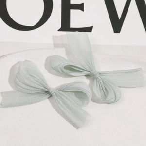 Detailed view of light green organza handmade bow hair clips on a stone tray