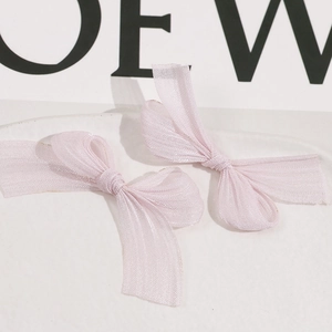 Detailed macro view of two pink organza handmade bow hair clips with sheer woven texture