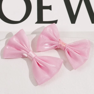 Detalle de dos pinzas para el cabello con lazo de malla rosa hechas a mano en bandeja