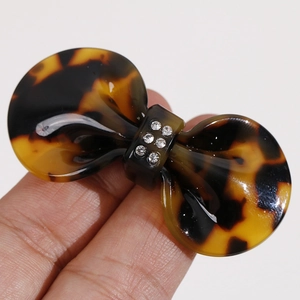 Macro shot of tortoise shell bow hair clip featuring embedded rhinestones and glossy texture