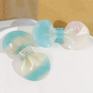 Macro shot of gradient pearlescent butterfly bow hair clips with rhinestones in a tray