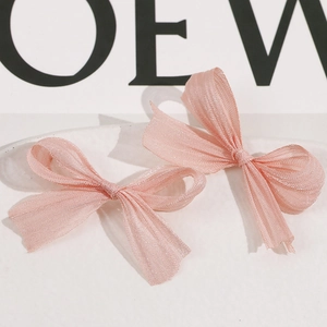 Detail of two pink organza bow hair clips showing soft pleated texture and lightweight fabric