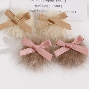 Détail de barrettes à nœuds en tissu crème et rose faites main avec pompons en peluche