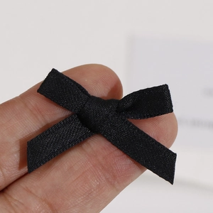 Gros plan d'un petit nœud en ruban gros-grain noir fait main posé sur un doigt