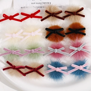 Macro shot of assorted velvet bow hair clips with faux fur balls in various winter colors