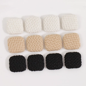 Close-up of square woven fabric buttons in white, beige and black for DIY jewelry making