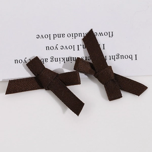 Paire de barrettes à nœud en ruban marron foncé en tissu texturé sur carte blanche