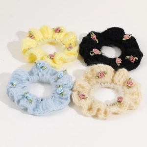 Close-up of four knitted elastic hair ties with colorful ribbon roses in soft pastel tones