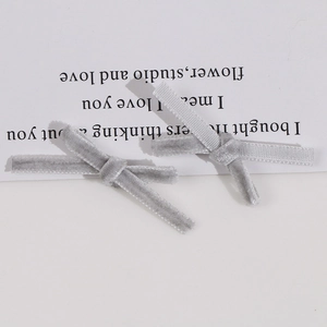 Macro detail of handmade grey velvet bow tie hair clip accessories on white card