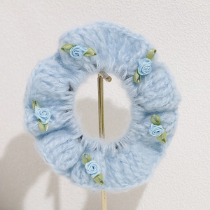 Blue knit hair scrunchie with five handmade ribbon roses on a metal display stand