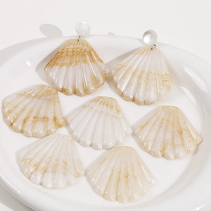 Gros plan de pendentifs en résine en forme de coquillage blanc crème pour bijoux DIY