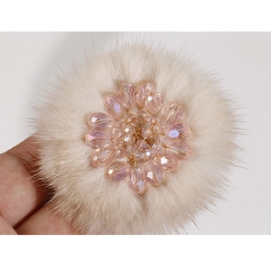 Macro detail of plush flower hair accessory with pink crystal beads and soft beige faux fur