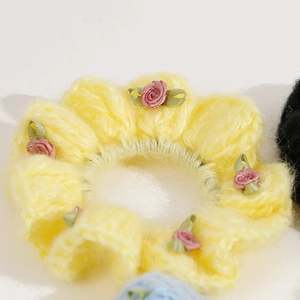 Detail of yellow knit hair tie featuring small pink ribbon roses and leaf accents