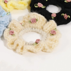 Macro view of knit crochet scrunchies with delicate ribbon roses and leaf details