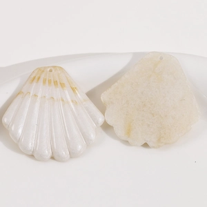 Vue détaillée de pendentifs coquillages crème avec textures et trous pré-percés pour bijoux