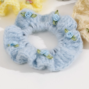 Close-up of light blue knitted hair tie with delicate rose floral embroidery detail