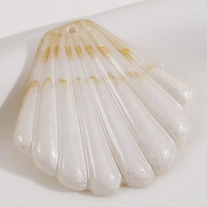 Détail macro du pendentif coquillage en résine nacrée avec trou pré-percé pour bijoux