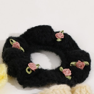 Detailed texture of black knitted hair scrunchie with delicate pink ribbon roses