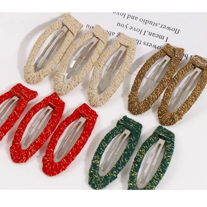 Close-up of fabric woven hair clips in beige, brown, red, and green with metallic threads