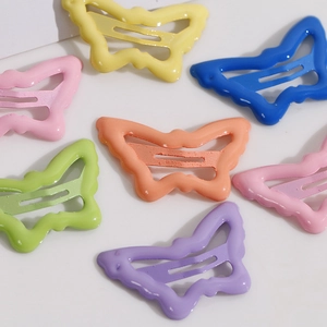 Dettaglio delle mollette per capelli a farfalla in metallo colorato in toni macaron