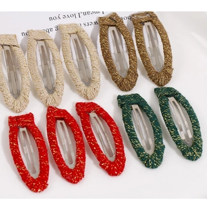 Detailed view of handmade woven fabric hair clips in cream, bronze, red, and green colors
