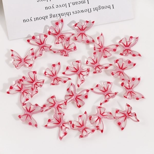 Detail of pink translucent butterfly pendants with red dots and radial lines for DIY jewelry
