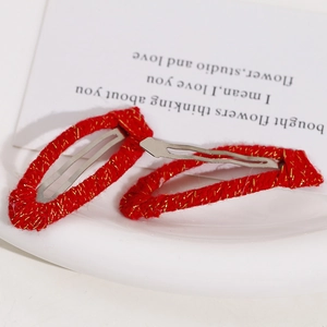 Detailed view of red woven hair clips with gold threads and silver metal base