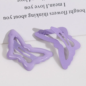 Dettaglio di due fermagli per capelli a farfalla viola lavanda con design traforato