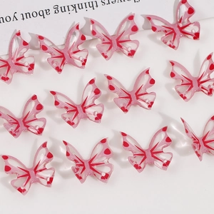 Macro view of translucent pink resin butterfly charms with red heart dots and pre-drilled holes