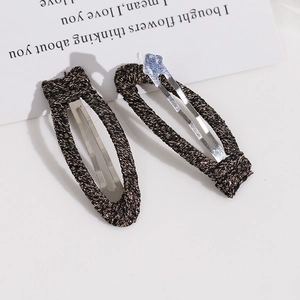 Detailstruktur stoffumwickelter Metall-Haarclips in Schwarz und Dunkelbraun