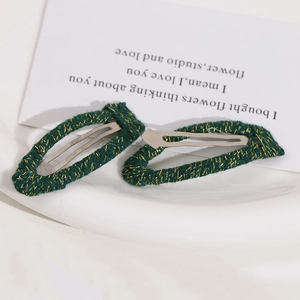 Close-up of green and gold woven fabric wrapping on metal elastic hair clips