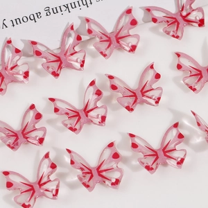 Detailed view of translucent pink butterfly pendants with heart patterns for DIY jewelry