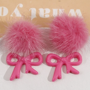 Detail of pink faux fur pom poms and resin bow patches for DIY jewelry making