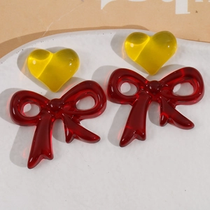 Macro detail of red and yellow resin bow charms with glossy jelly texture for DIY jewelry