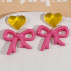 Macro shot of yellow resin hearts and pink bows for DIY earring jewelry making