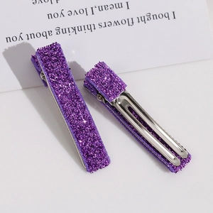 Détail de deux barrettes à cheveux violettes pailletées avec base en métal argenté