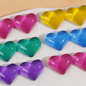 Macro-opname van kleurrijke doorschijnende hartvormige harsbedeltjes met kattenoogeffect voor DIY