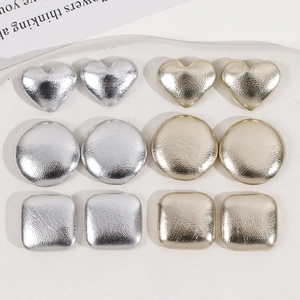 Macro detail of geometric heart and square faux-leather metallic DIY jewelry parts