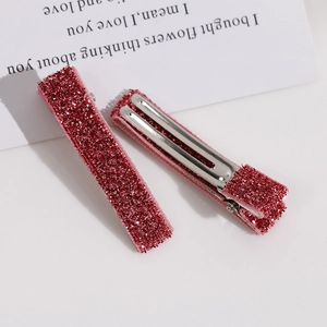 Détail des barrettes à cheveux en métal recouvertes de tissu à paillettes rose vif