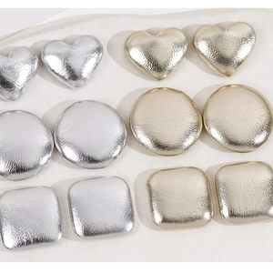 Macro detail of geometric heart, round, and square metal accessories with leather texture