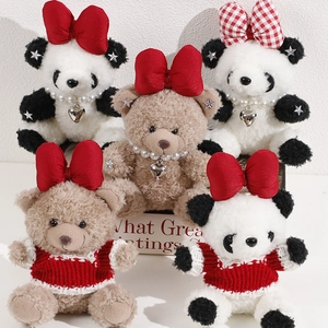 Close-up of plush panda and bear toys with red bows, knit sweaters and pearl necklaces