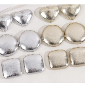 Close-up of geometric textured metal buttons in gold and silver heart and circle shapes