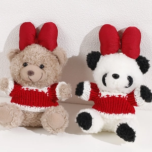 Close-up of plush teddy bear and panda toys wearing red sweaters and satin bows