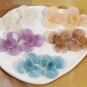 Détail de fleurs en acétate à 3 pétales aux couleurs dégradées sur un plateau blanc