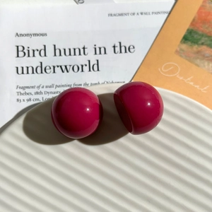 Orecchini a perno a sfera in resina rosso rosa lucido su vassoio decorativo