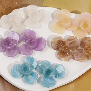 Gros plan de charmes fleurs 3D en acétate avec texture marbrée pour création de bijoux