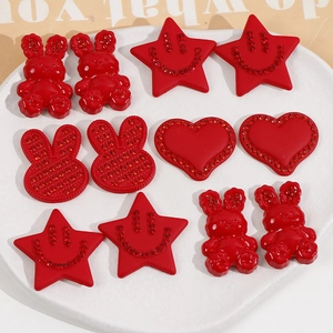 Macro shot of red acrylic star, heart, and rabbit charms with glittering rhinestones