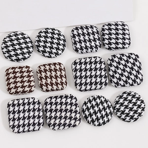 Detail view of round and square houndstooth fabric buttons in black and brown patterns