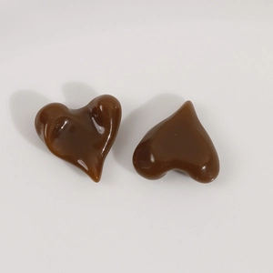 Macro detail of glossy brown resin heart charms with irregular concave surfaces for DIY jewelry