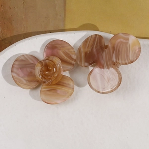 Détail macro de pinces à cheveux fleurs en acétate avec texture marbrée rose et marron